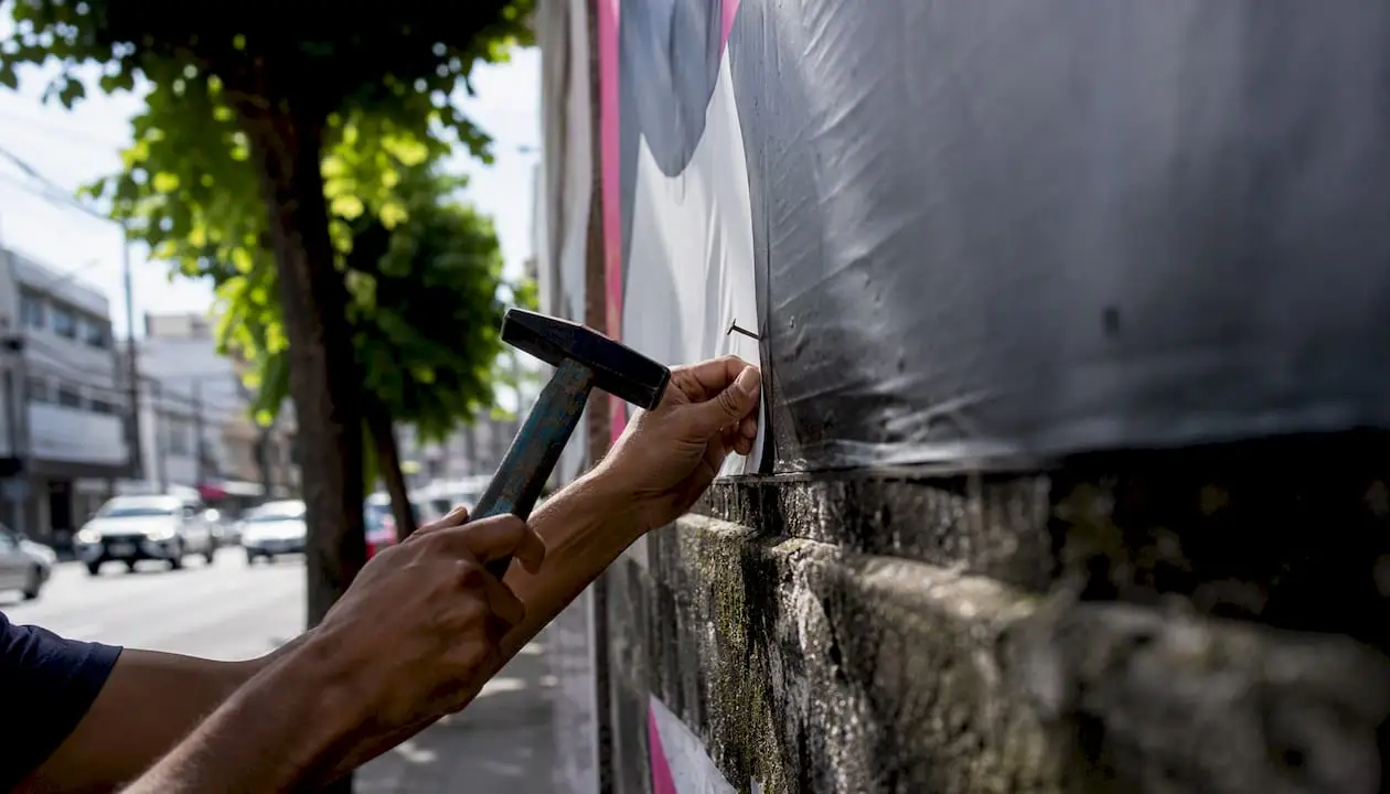Mãos a aplicar materiais publicitários em espaços urbanos